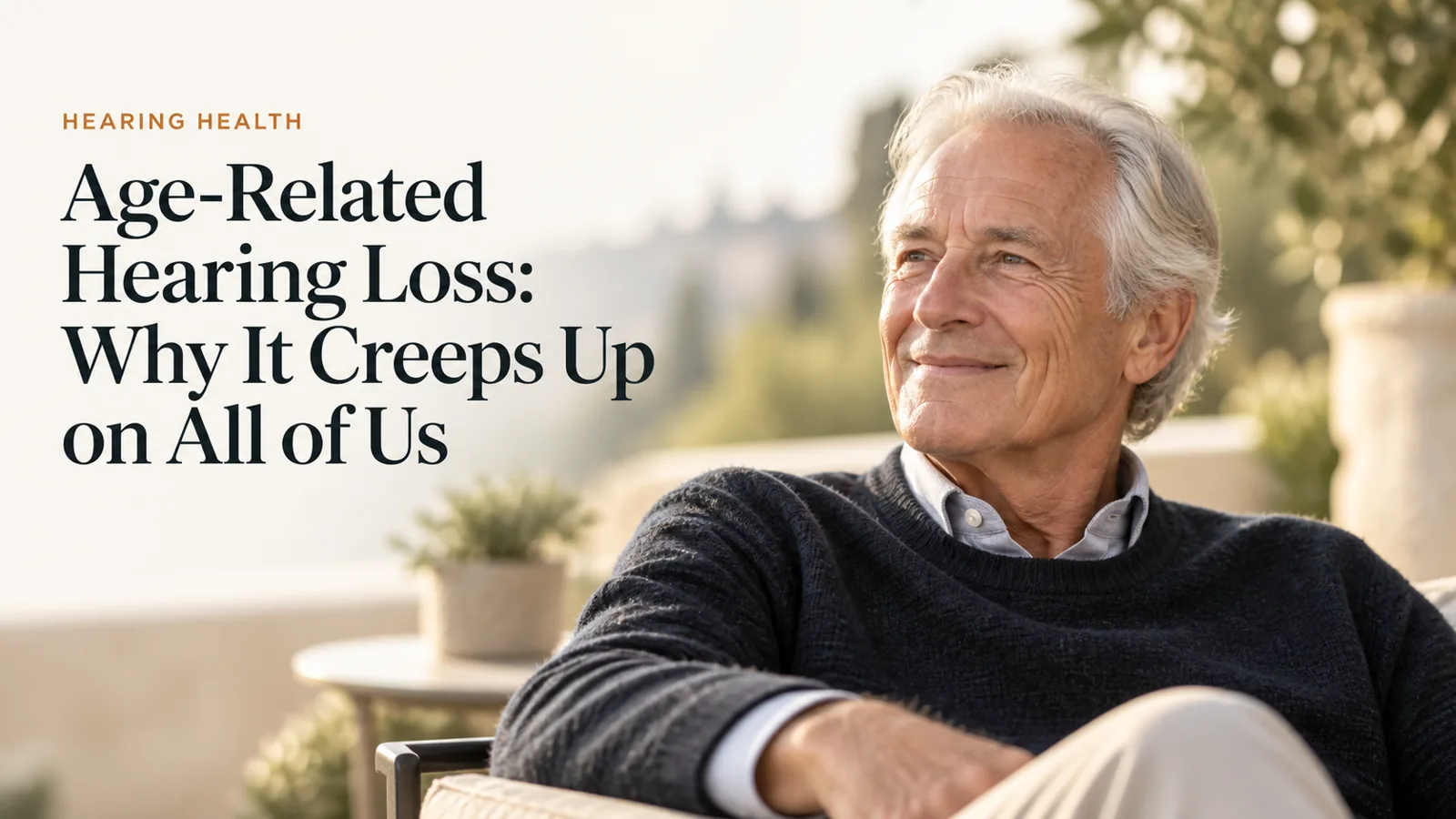 A distinguished older man smiling gently outdoors in natural light.