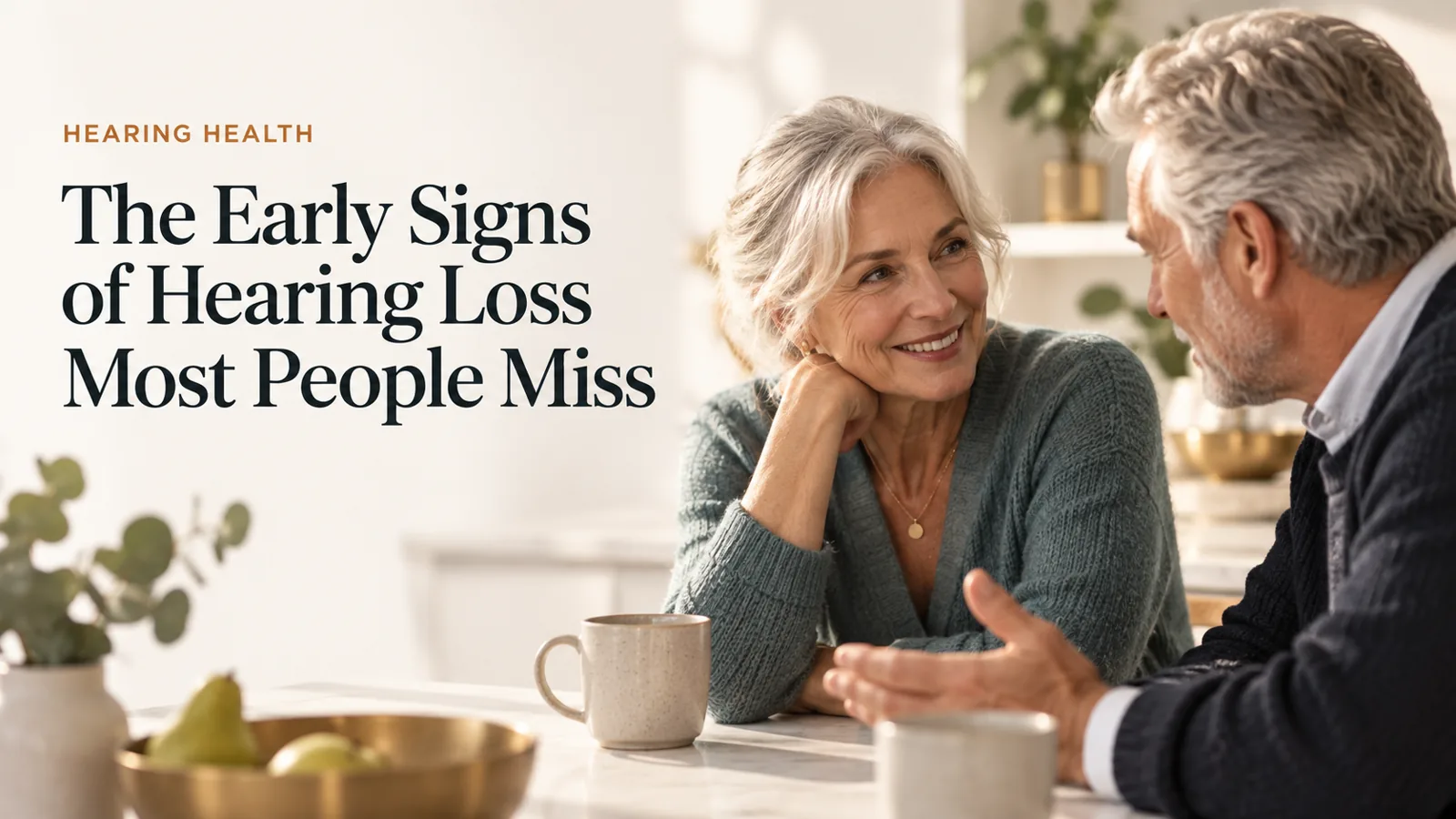 Two older adults leaning in close during a warm conversation at a kitchen table.